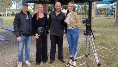 Blind filmmaker Gough standing with the cast and crew in a field in front of a pagoda for his film
