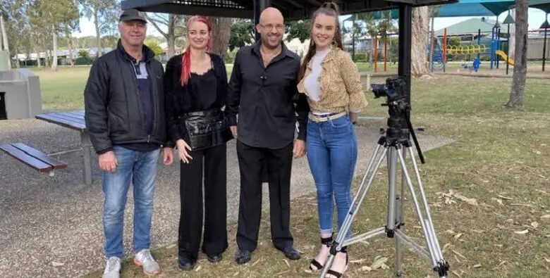 Blind filmmaker Gough standing with the cast and crew in a field in front of a pagoda for his film