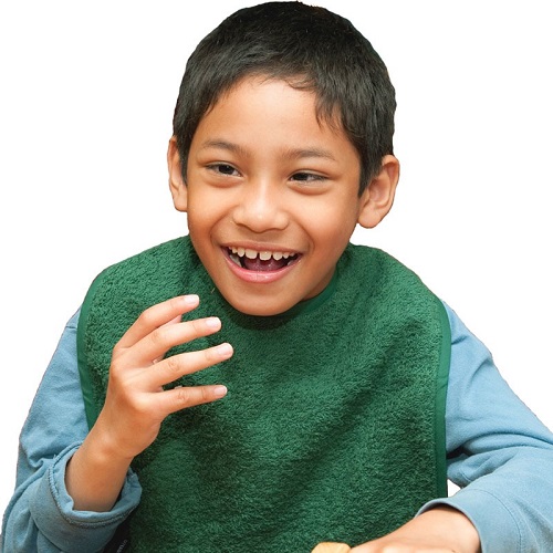 Young boy smiling wearing a green Seenin apron over a blue shirt