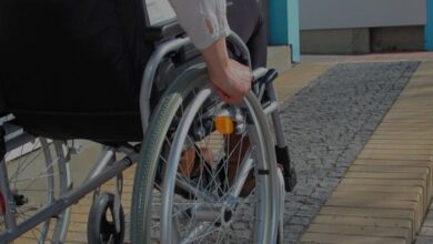 Wheelchair user going up a paved ramp in a manual chair being viewed from behind