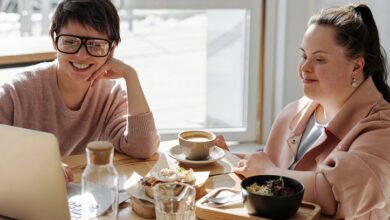 Woman with Down's Syndrome sat at a table with another woman using a laptop