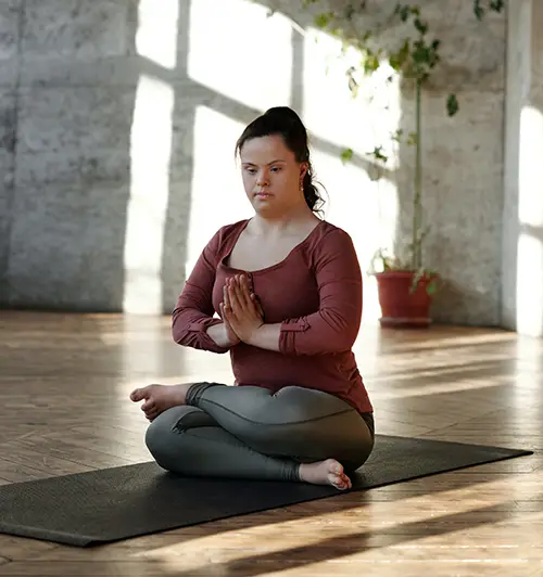 A lady, who has down syndrome, is in a sitting yoga position - Photo by Cliff Booth from Pexels