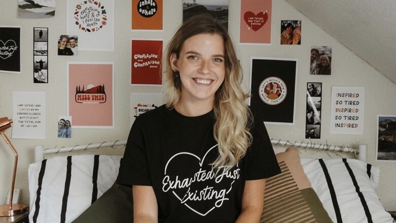 Blogger Jenny sat on her bed wearing a black T-shirt that says exhausted just existing with her illustrations on the wall behind her