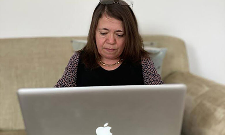 Emma is sitting on the sofa and is working on her laptop - Photo by Emma West