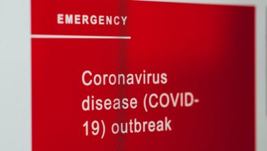 Red sign with white writing saying emegency coronavirus disease Covid-19 outbreak