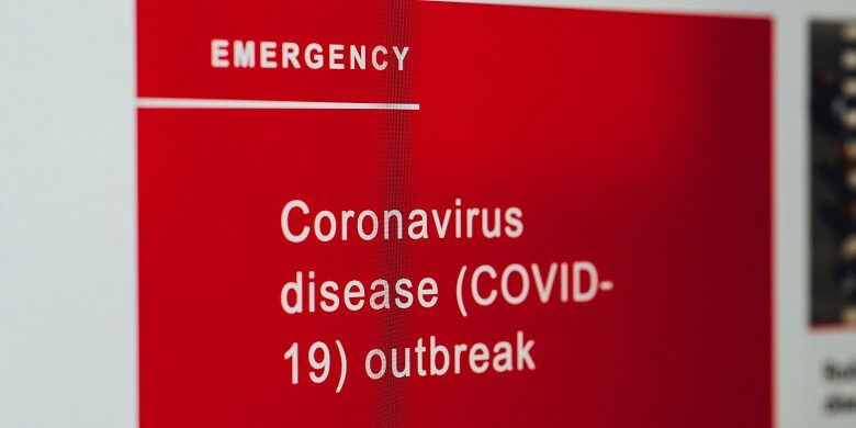 Red sign with white writing saying emegency coronavirus disease Covid-19 outbreak