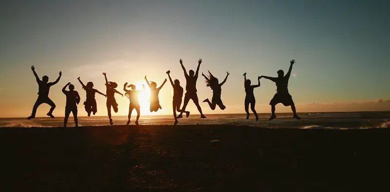 Group of people seen in silhouette on a beach in front of the sea