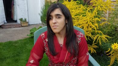 Zubee Kibria sat in the garden wearing a red and gold embellished sari