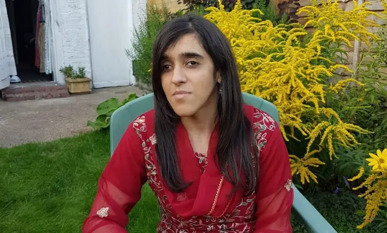 Zubee Kibria sat in the garden wearing a red and gold embellished sari