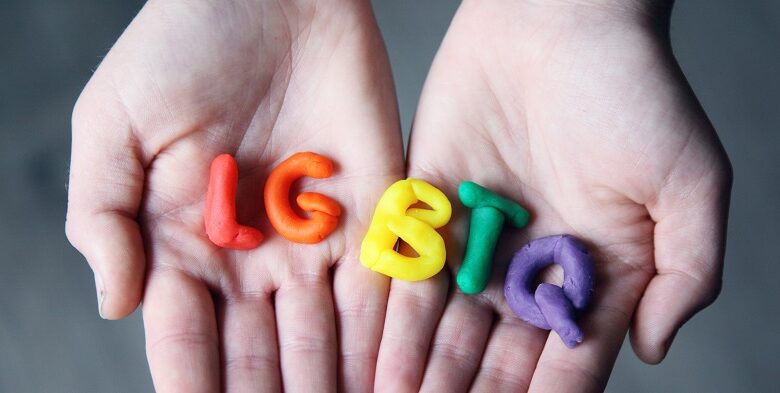 LGBTQ letters in rainbow colours help in someone's hands