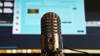 Microphone in front of a computer screen slightly blurred recording a podcast