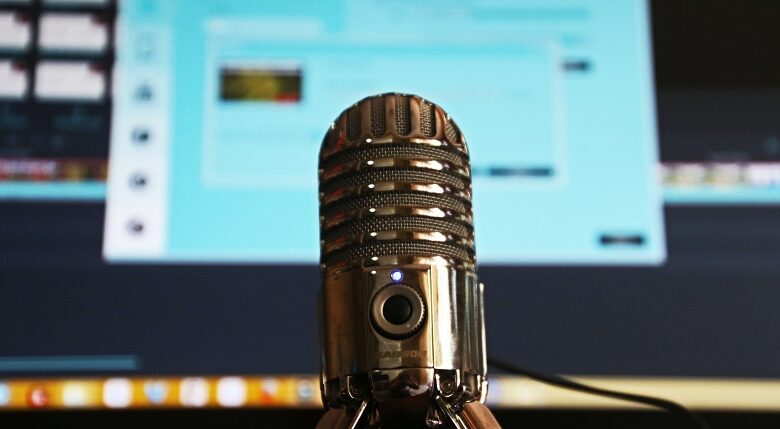 Microphone in front of a computer screen slightly blurred recording a podcast