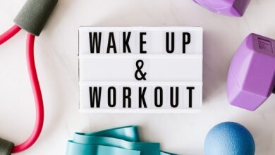 Wake up and work out sign surrounded by purple weights, a turquise elastic band and arm exerciser