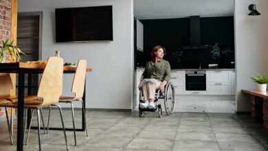 Woman using a wheelchair wheeling out from her open-plan kitchen into her dining room