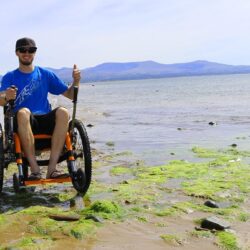 Tim Morgan in his Mountain Trike all-terrain wheelchair on a rocky beach