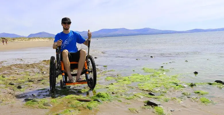 Tim Morgan in his Mountain Trike all-terrain wheelchair on a rocky beach