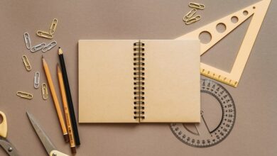 A notepad, pencils, paper clips and rulers on a brown background