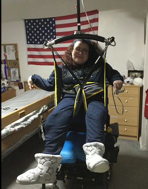 Emma Purcell in her sling being raised by a ceiling hoist from her wheelchair