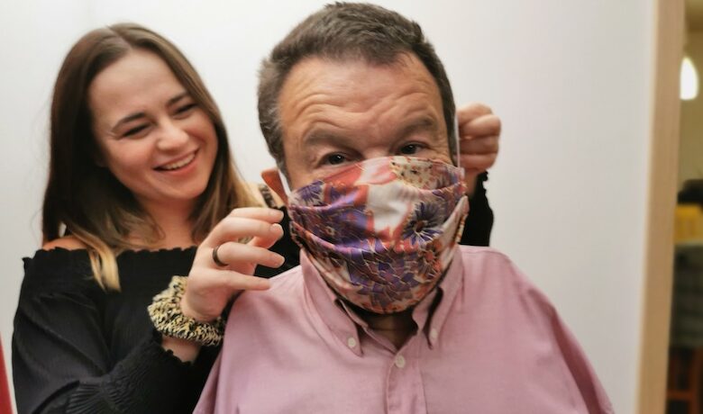 Holly Yendell helping her father Tom put on a patterned face mask