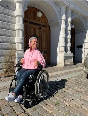 Woman in manual wheelchair modelling pink jersey cape