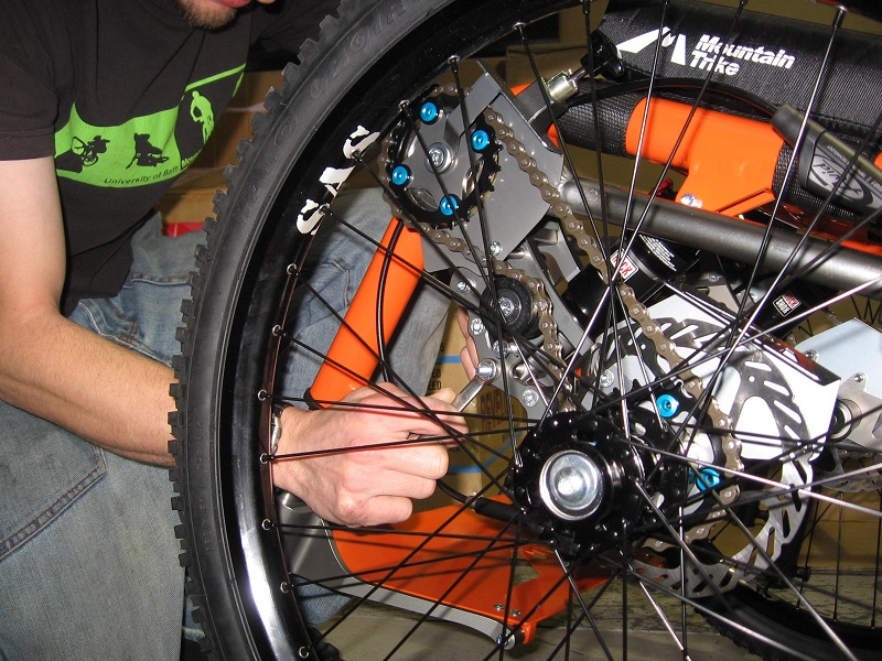 A man cleaning the drive chain on a Mountain Trike all-terrain wheelchair