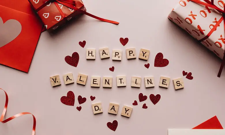 Happy Valentine's Day written in scrabble letters with hearts and gifts in red wrapping paper around them