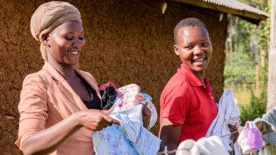 Two black women in Africa carrying washing smiling