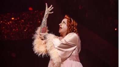 Anna on stage doing burlesque dancing holding up her right arm up with her left arm