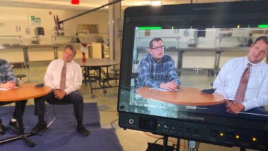 Jacob Flax and Evan Taylor from The Guild for Human Services sitting at a desk behind a camera filming