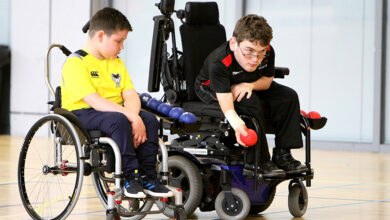 Two young boys playing boccia from their wheelchairs