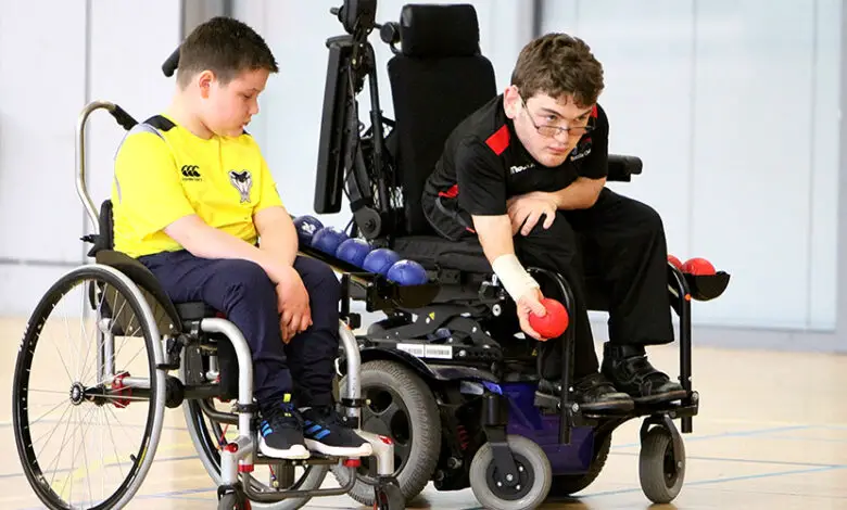 Two young boys playing boccia from their wheelchairs