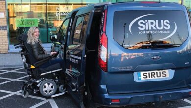 Woman in a power wheelchair going up a ramp at the side of an adapted vehicle
