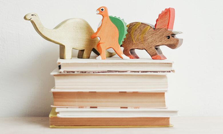 A pile of books with wooden kids toys on top of them