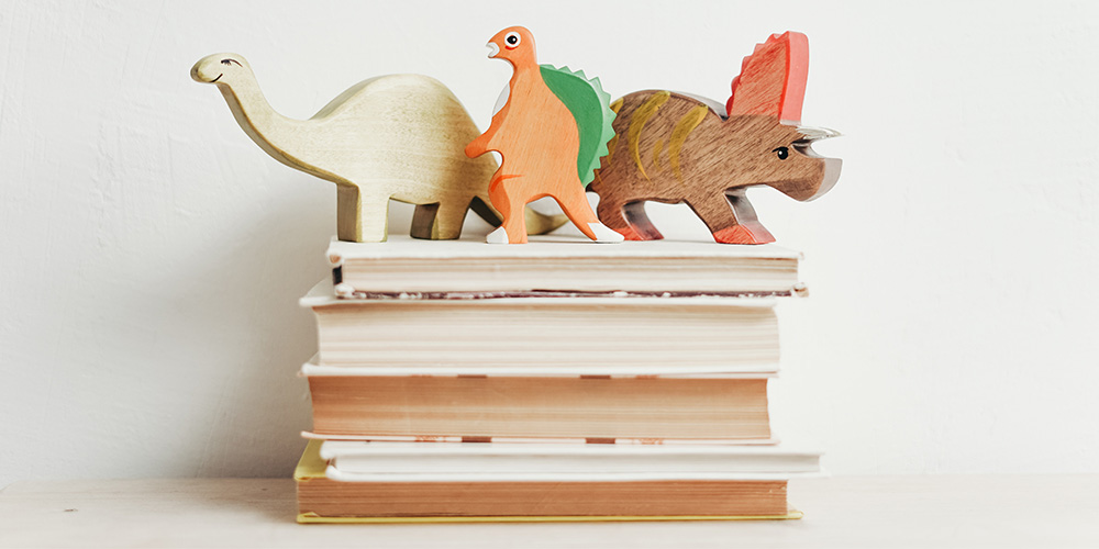 A pile of books with wooden kids toys on top of them