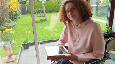 Hannah Deakin in her wheelchail holding a notebook