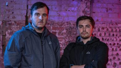 Deaf contestants James and Nathan on Hunted standing wearing grey and black jackets in front of a wall
