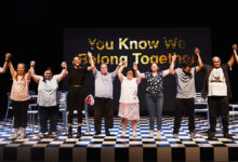 - Cast of We Know We Belong Together on stage about to take a bow. The background is black and there is a black and white chequered floor