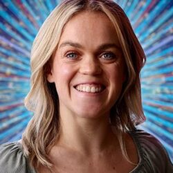 Paralympian Ellie Simmonds on Strictly Come Dancing 2022. She has shoulder length light brown hair and is wearing a beige top, standing in front of a sparkly blue background