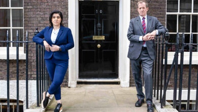 Baroness Sayeeda Wars in a blue suit with Alastair Campbell in a grey suit stood either side of the No 10 Downing Street door for Make Me Prime Minister