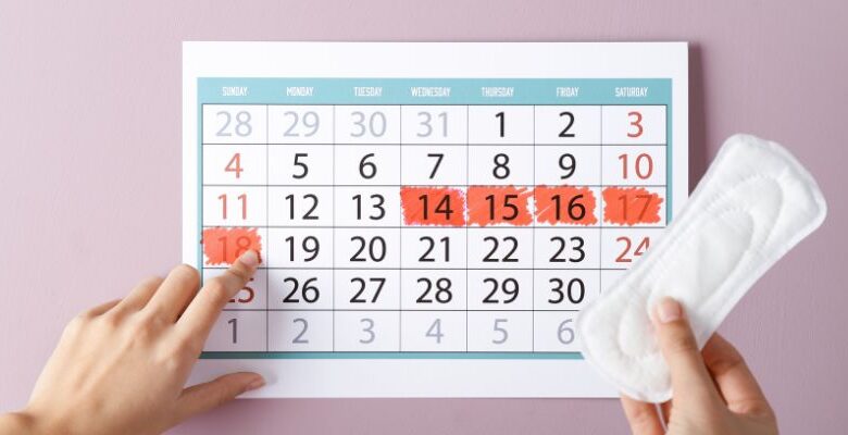 A calendar showing a month with 7 days marked in red and a sanitary towel next to it