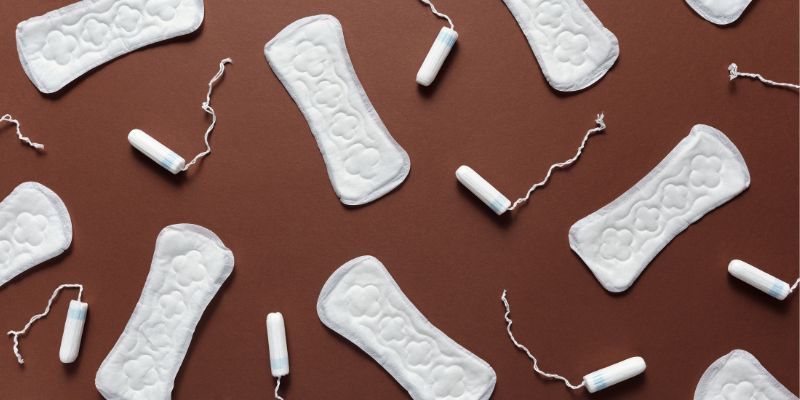 A number of white sanitary towels and tampons lying on a brown background