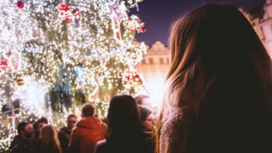 A queue of people waiting to see a tall Christmas tree covered in lights and decorations