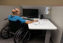 A man in a wheelchair using headphones with his computer