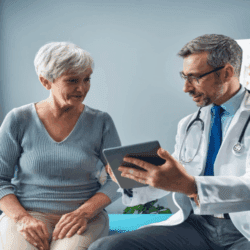 Doctor shows an older woman something on a tablet during a consultation in a medical office