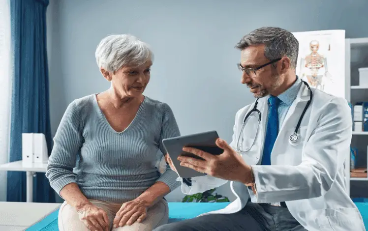 Doctor shows an older woman something on a tablet during a consultation in a medical office