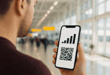 A person at an airport holds a smartphone displaying a signal strength icon above a QR code, showing eSIM activation.