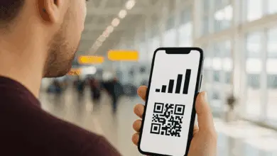 A person at an airport holds a smartphone displaying a signal strength icon above a QR code, showing eSIM activation.