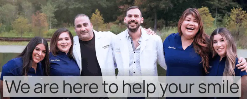 Six smiling dental staff in navy and white coats standing arm-in-arm outdoors, with text reading “We are here to help your smile.”