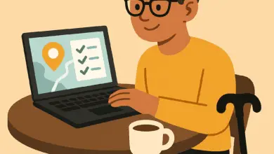 Flat cartoon illustration of a disabled traveler with short brown hair, glasses, and a hearing aid, sitting at a café table with a laptop. A coffee cup sits on the table and a cane leans against the chair. The laptop screen shows a map and a checklist.