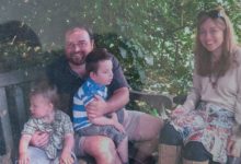Duncan as a family carer outdoors with his partner and two young children, one sitting on his lap.